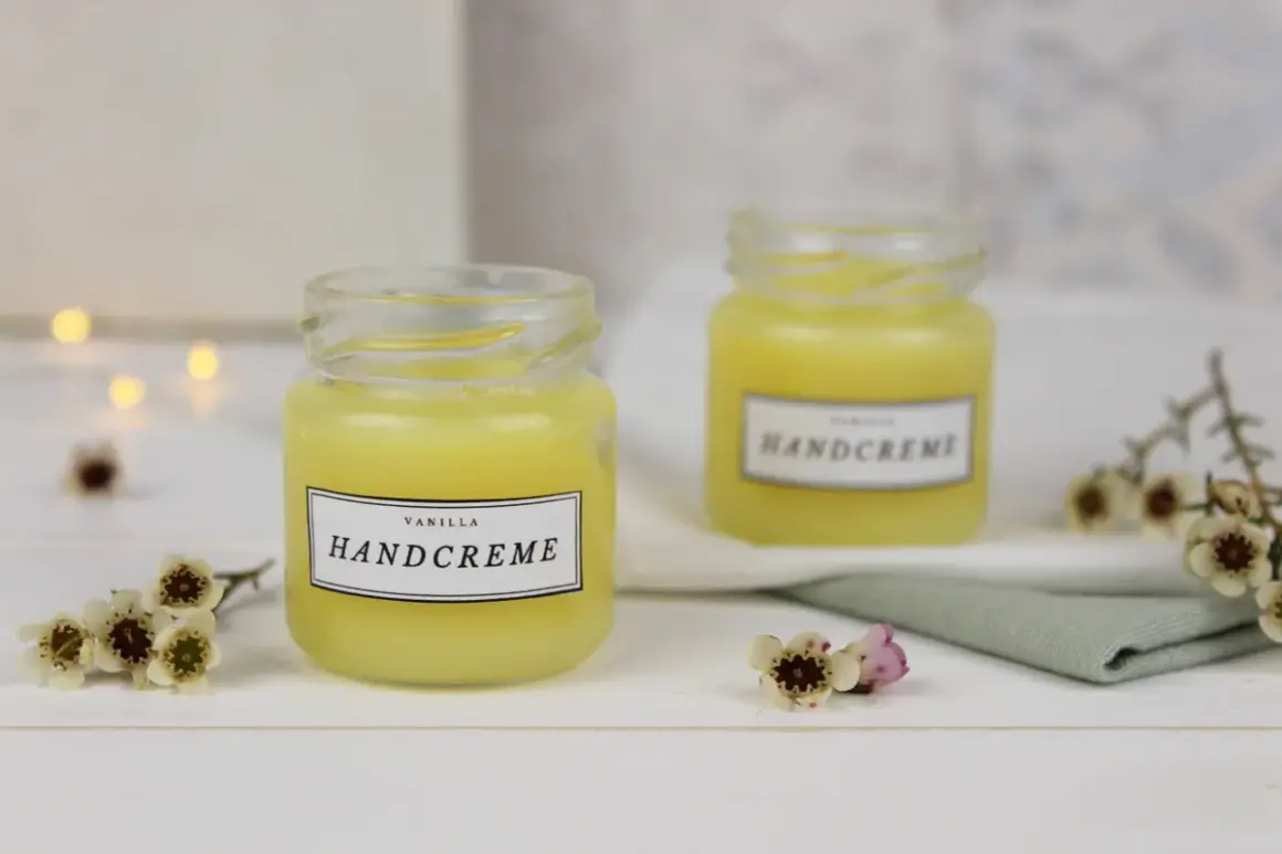 Zwei Gläser mit selbstgemachter Handcreme, verziert mit kleinen Blüten. Perfekt zum Handcreme selber machen für Kinder.