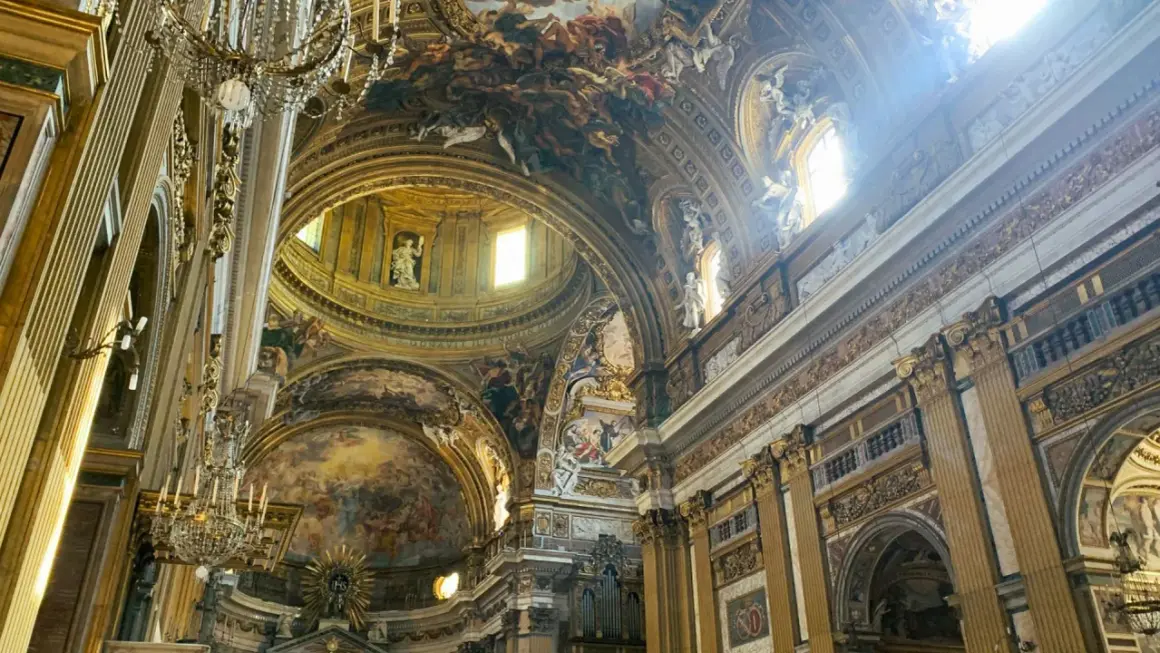 Interno della chiesa del Gesù, con affreschi barocchi sul soffitto, cupola e decorazioni dorate.