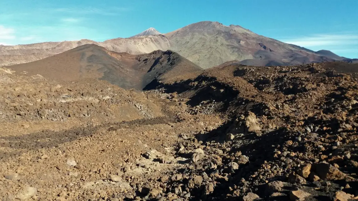Paisaje volcánico árido visto desde el mirador de Samara, con montañas y conos de ceniza bajo un cielo azul.