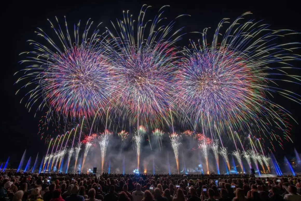 Spectacle pyrotechnique grandiose pour la fete du lac, illuminant le ciel nocturne de gerbes multicolores au-dessus d'une foule admirative.