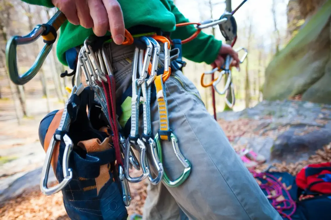Kletterer mit Ausrüstung für trad climbing, darunter Kletterschuhe und Karabiner, bereit für den Aufstieg.