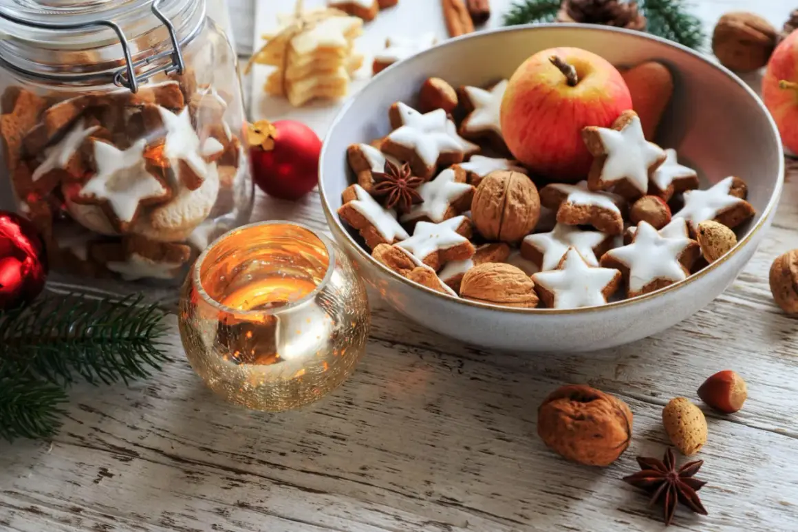 Weihnachtsplätzchen, Nüsse und ein Apfel in einer Schale, dazu eine Kerze – das ist die Bedeutung von Weihnachten: Gemütlichkeit und Genuss.