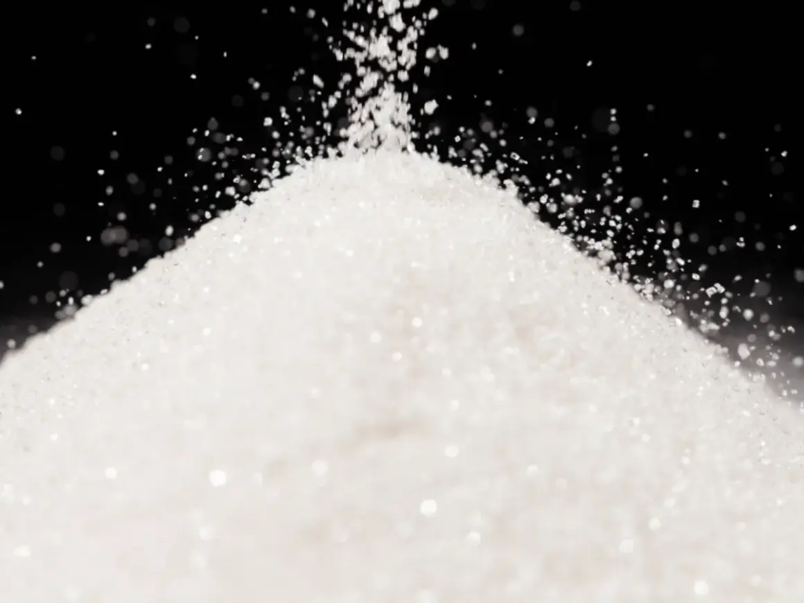 Biały, drobny proszek, przypominający cukier lub sorbitol, sypie się na stożek.
