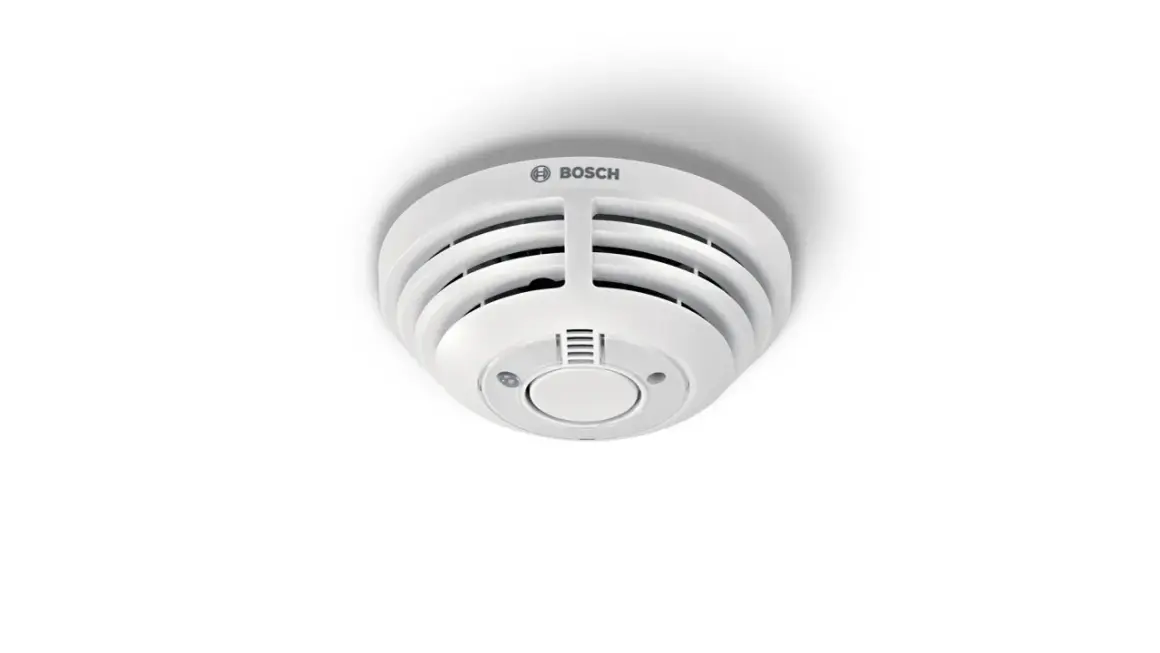 Ein weißer Bosch Smart Home Rauchmelder blinkt rot, was auf eine mögliche Gefahr hinweist.