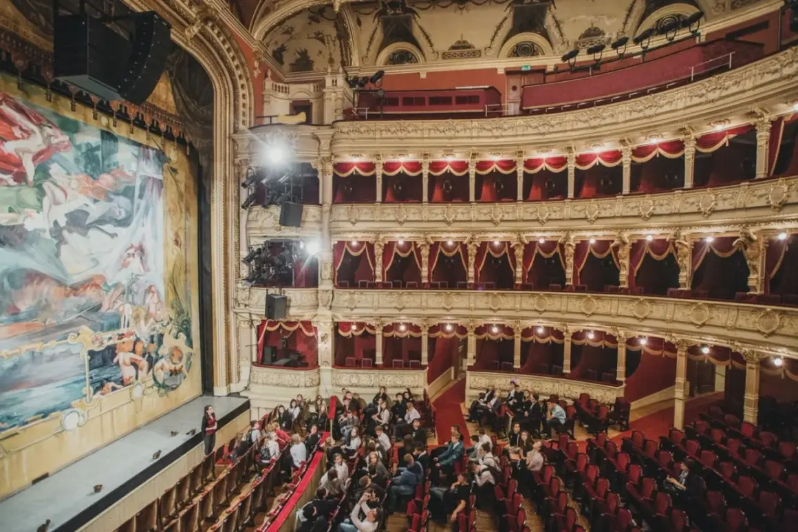 Widownia teatru w Krakowie, gdzie warto iść na spektakl. Złote zdobienia, czerwone aksamitne obicia i wielki malowany kurtyna tworzą magiczną atmosferę.