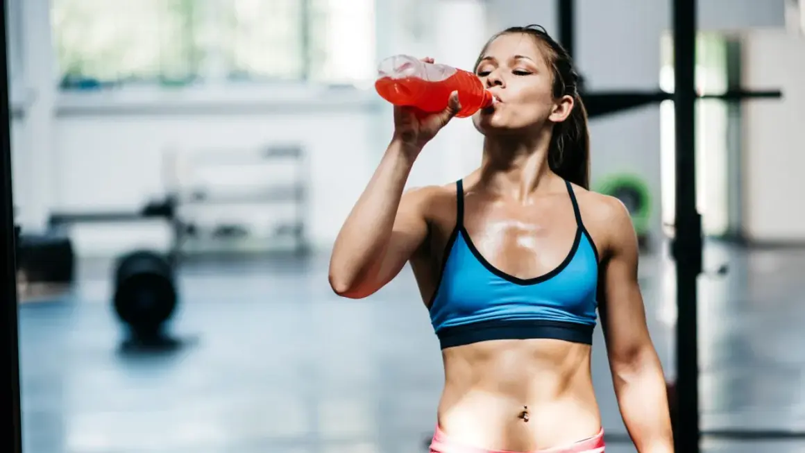 Eine Frau trinkt nach dem Training ein isotonisches Getränk. Es hilft, den Flüssigkeits- und Elektrolythaushalt auszugleichen.