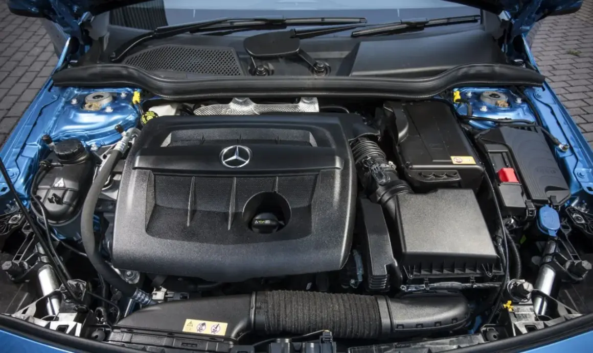 Motor de un Mercedes Clase A 180 gasolina, con su tapa negra y el logo de la estrella.
