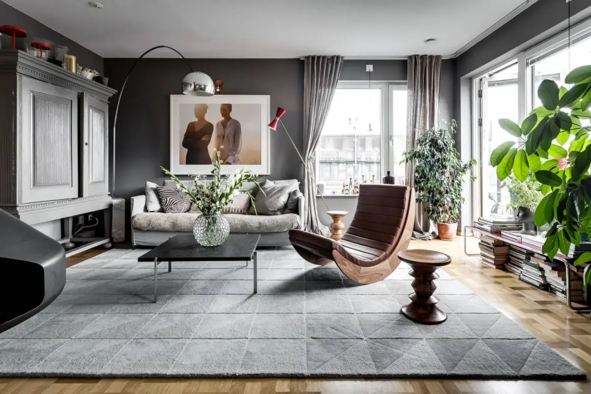 Stilvolles Wohnzimmer in Grau mit gemütlicher Couch, Design-Sessel und viel Grün. Tolle wohnzimmer grau ideen für ein modernes Zuhause.