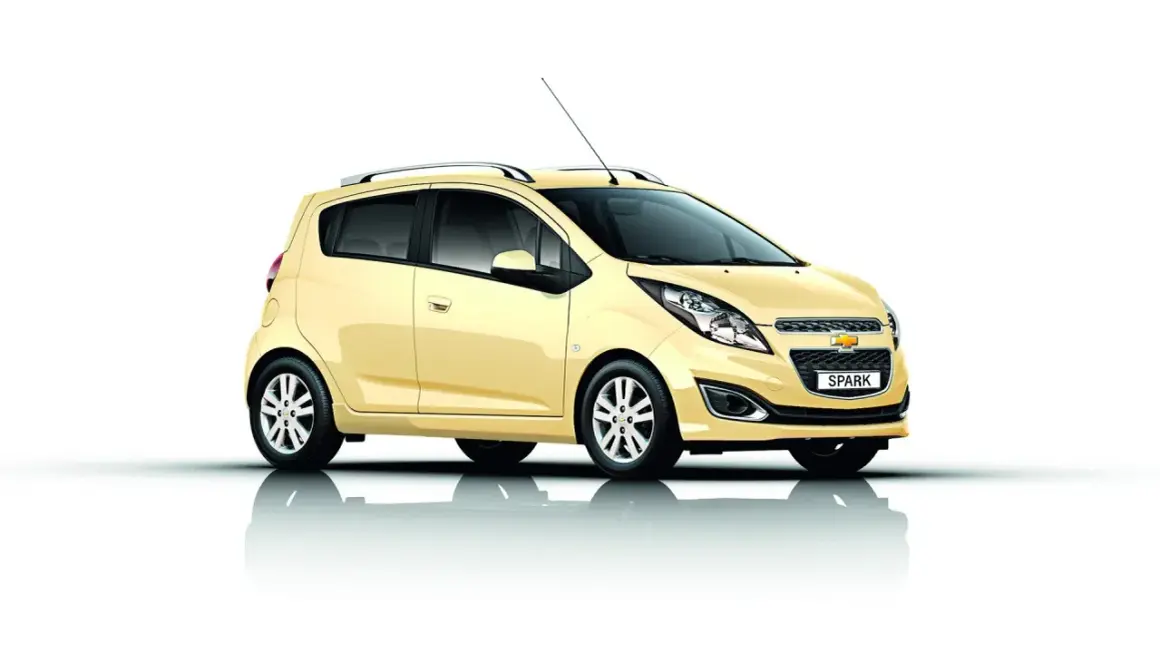 Żółty Chevrolet Spark, jeden z popularnych chevrolet modele, prezentuje się na białym tle.