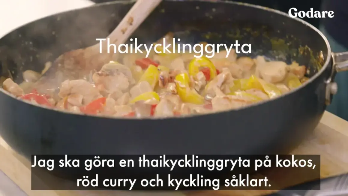 En thaikycklinggryta med kycklingbitar, gul och röd paprika i en krämig sås i en stekpanna.