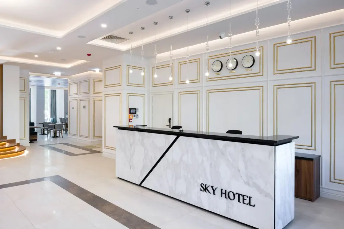 Eleganckie lobby hotelu Sky Kraków z marmurowym recepcjonistą i zegarami światowymi.