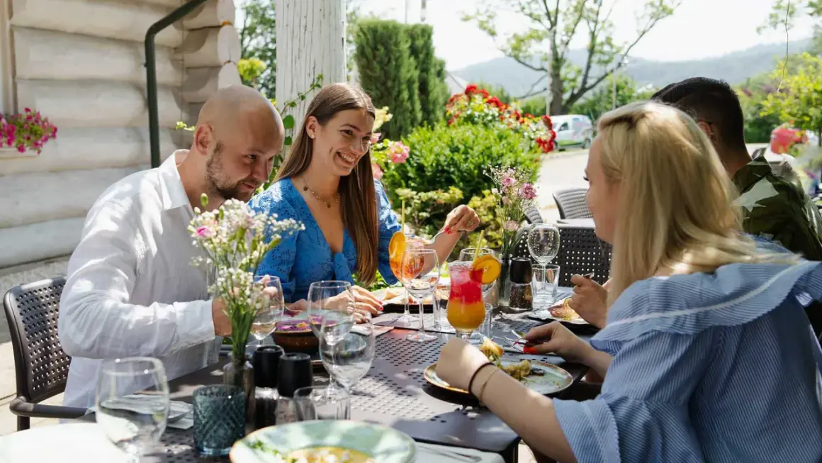Uśmiechnięci ludzie jedzą posiłek w jednej z restauracji w Bielsku i okolicach. Letni dzień sprzyja biesiadowaniu na świeżym powietrzu.