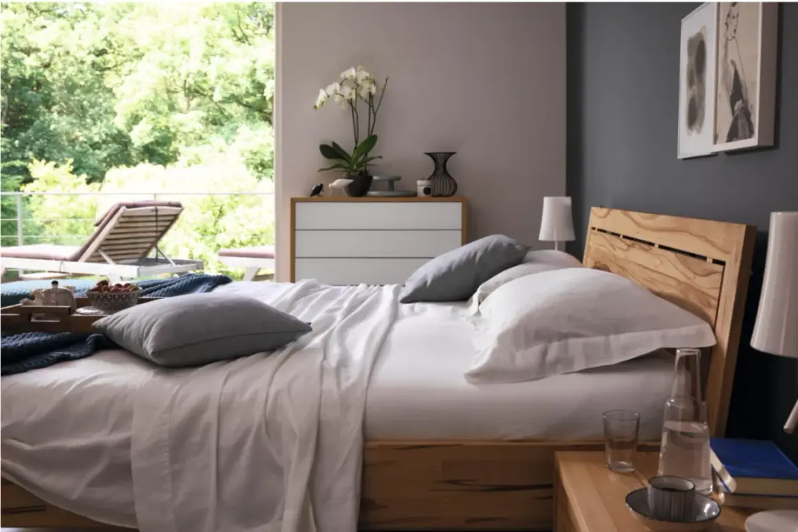 Gemütliches Schlafzimmer mit anthrazit Wand, Holzbett und Blick ins Grüne.