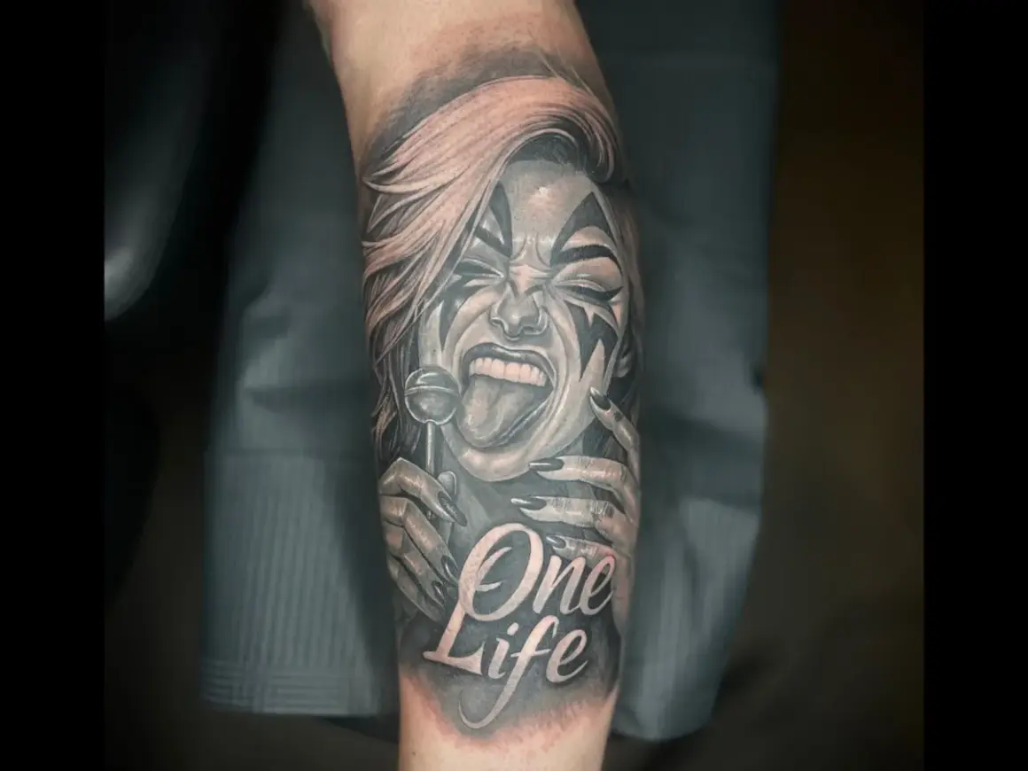 Ein detailreiches Tattoo mit einer Frau, die einen Lolli leckt, und der Aufschrift "One Life". Das Kunstwerk ist in Schwarz und Rot gehalten.