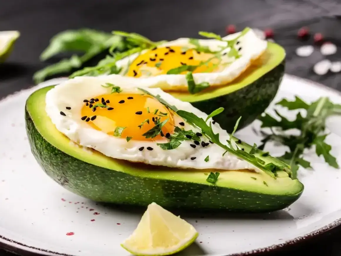 Pyszne i zdrowe dieta keto posilki: awokado zapiekane z jajkiem, posypane czarnuszką i rukolą.