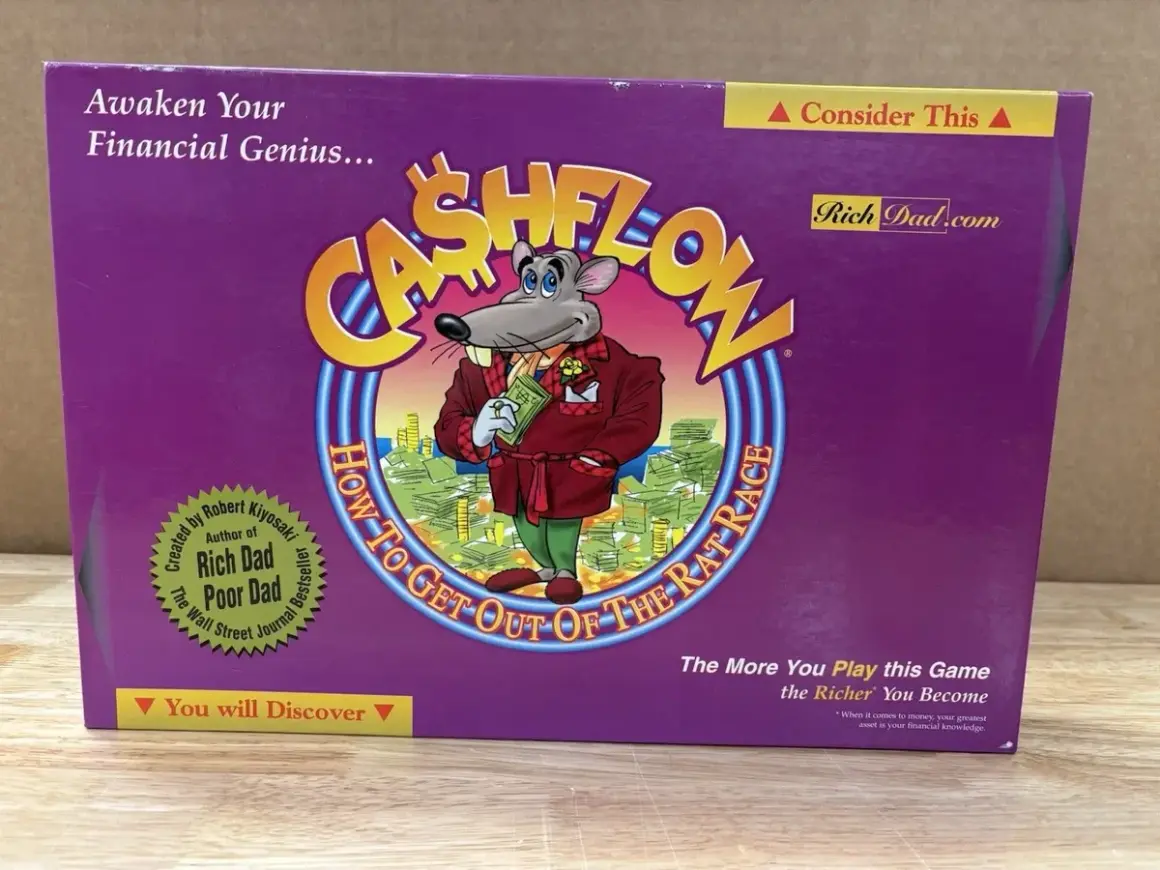 Das Cover des **Cashflow Spiels** zeigt eine Maus in einem Anzug, die Geld hält. Es ist ein Brettspiel, das finanzielle Bildung vermittelt.