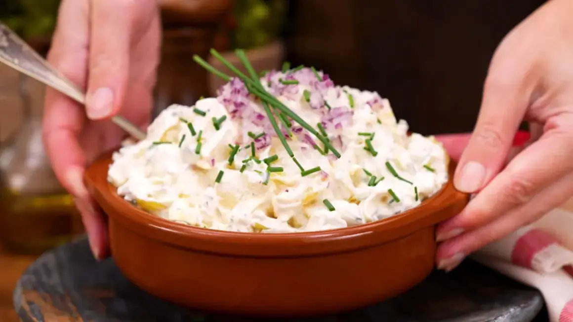 En skål med krämig potatissallad, toppad med rödlök och gräslök. Ett ljuvlig potatissallad recept som passar till allt!