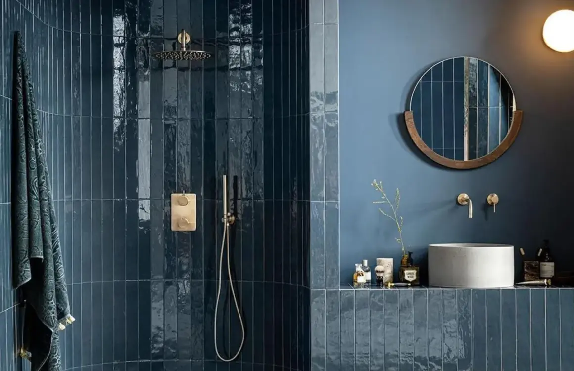 Élégante salle de bain bleu nuit avec douche à l'italienne carrelée, miroir rond en bois et vasque en béton.
