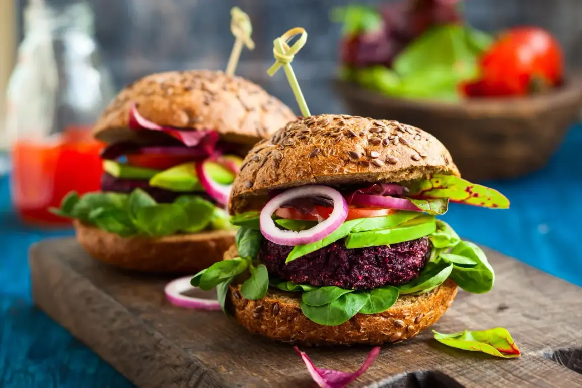 Zwei saftige vegane Burger mit Rote-Bete-Patty, Avocado, Tomate und Zwiebeln auf Vollkornbrötchen – perfekt für vegan zunehmen!