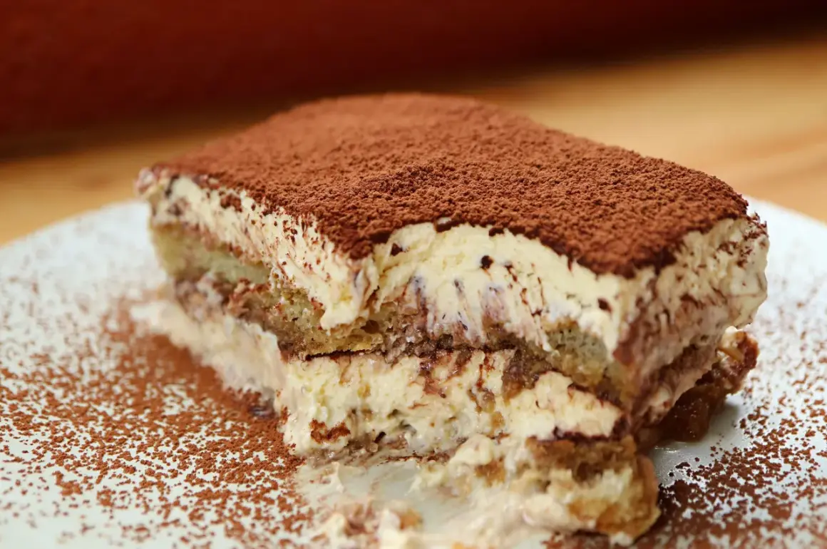 Una fetta di tiramisù, soffice e cremosa, cosparsa di cacao. Perfetta per un momento di dolcezza, anche in gravidanza.