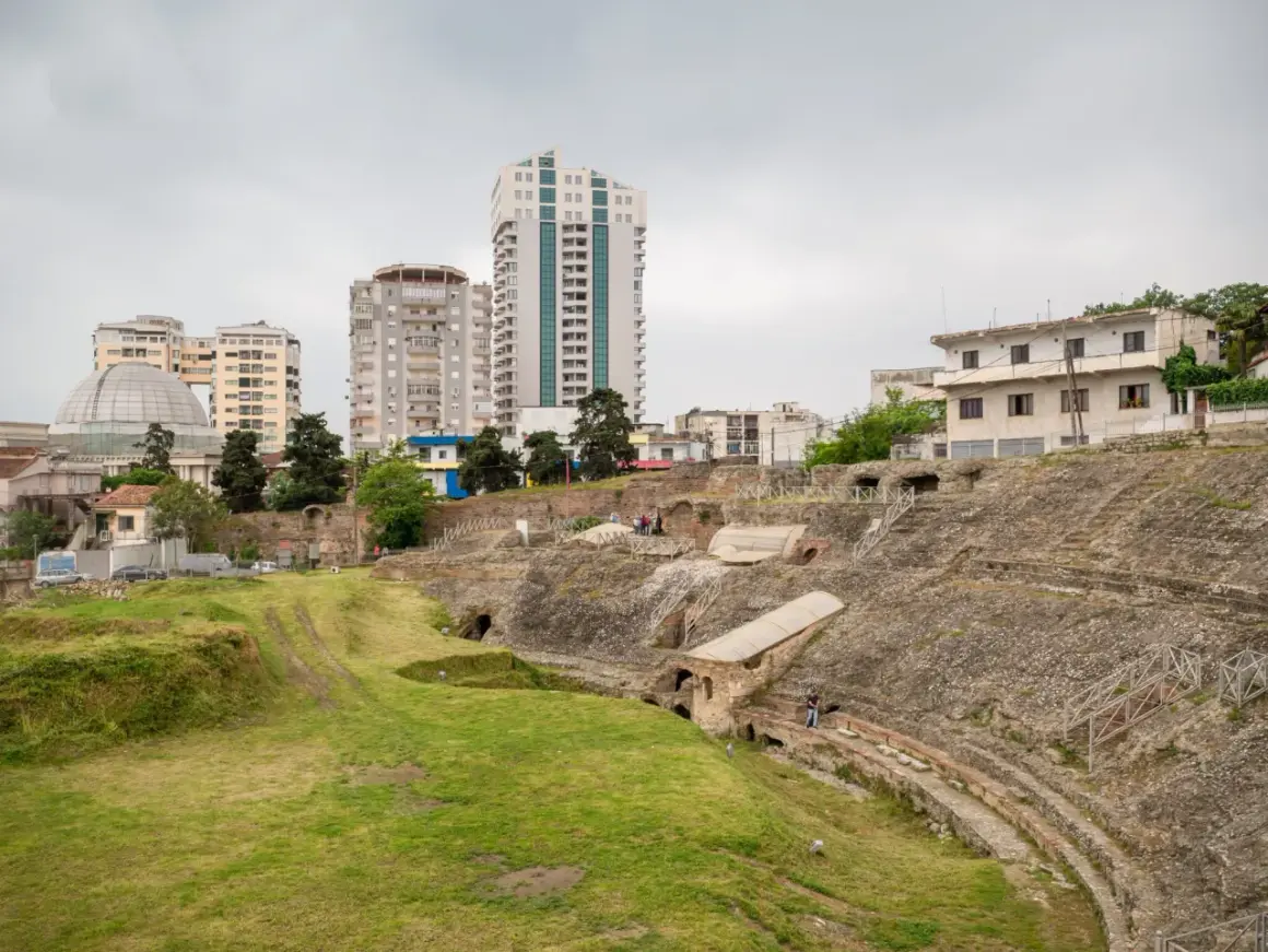 Ruiny amfiteatru w Durres, Albania, kontrastują z nowoczesnymi budynkami w tle.