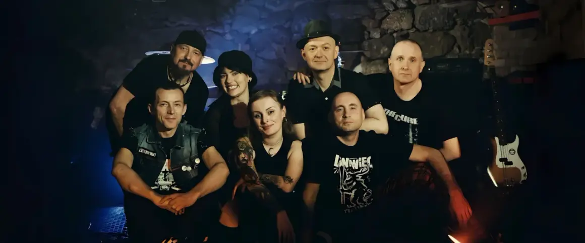 Grupa przyjaciół, zespół Leniwiec, pozuje do zdjęcia w mrocznym wnętrzu.