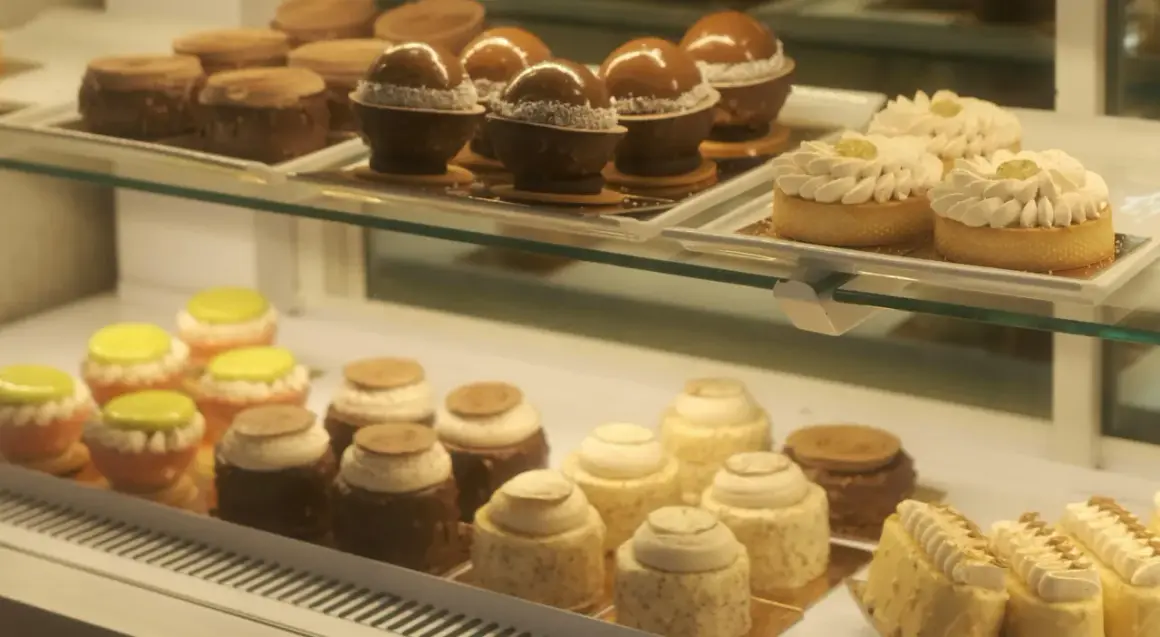 Słodkości w kawiarni cukierni Cafe Marona Gruszecki: czekoladowe kule, tartaletki z kremem i kolorowe babeczki.