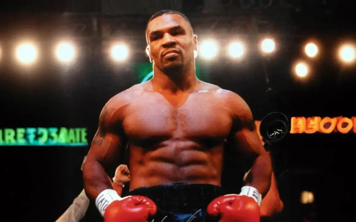 Mike Tyson's incredible build is on full display in the boxing ring, with red gloves ready.
