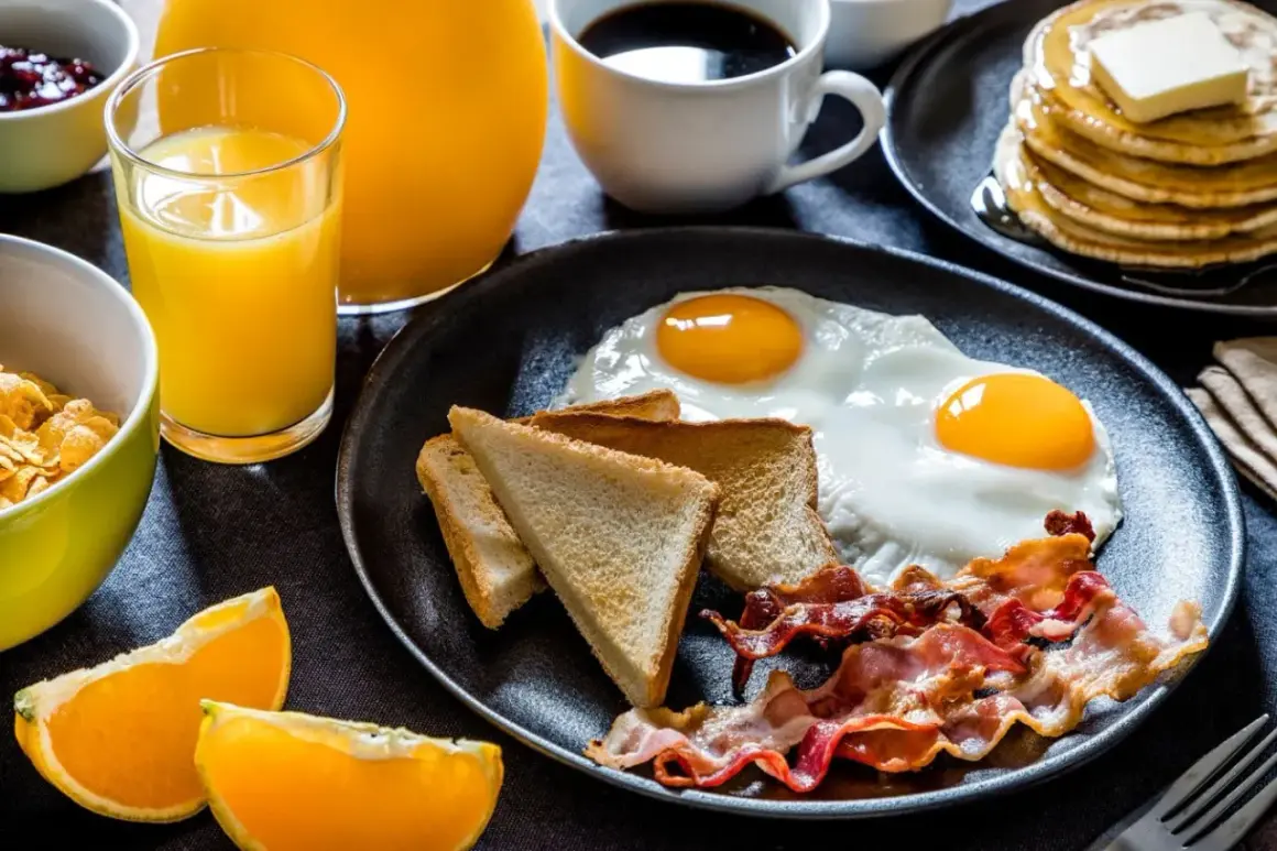 Un délicieux petit déjeuner salé avec des œufs au plat, du bacon croustillant, des toasts et du jus d'orange frais.
