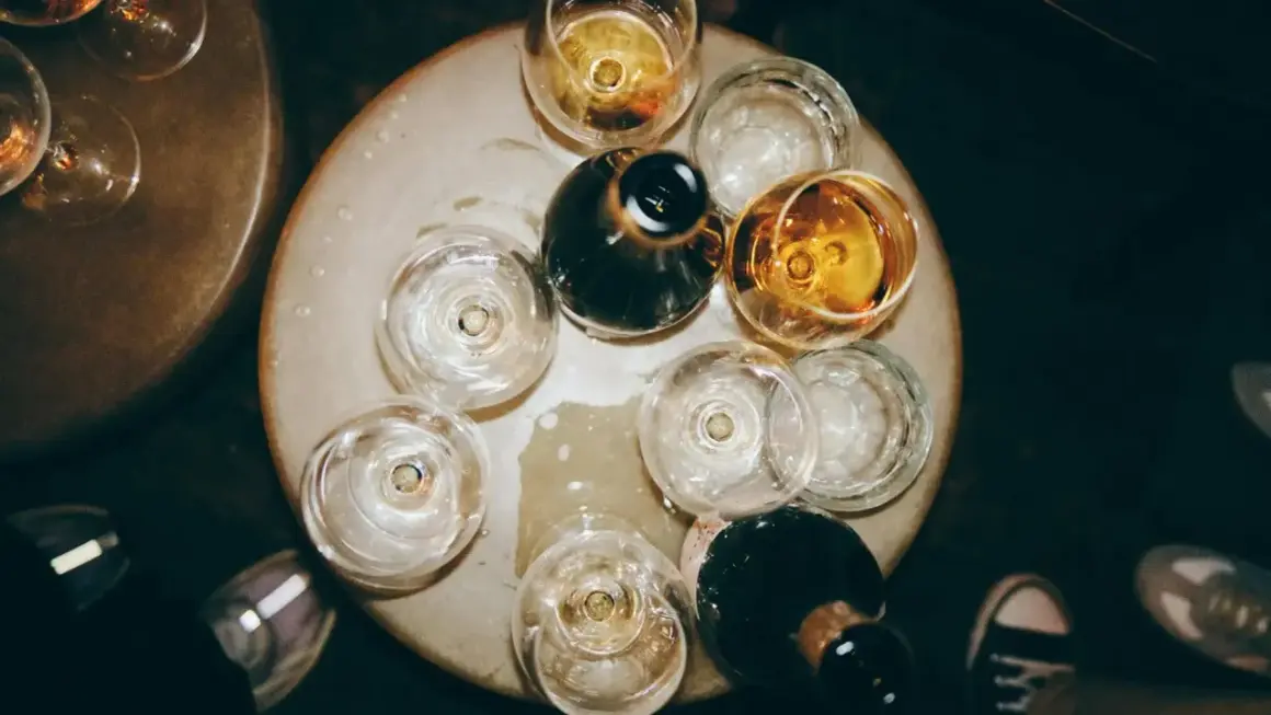 Naczynia z winem tworzą bukiet smaków i aromatów. Kilka kieliszków z bursztynowym trunkiem i ciemne butelki czekają na degustację.