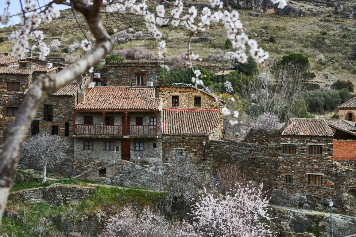 Casas de piedra con tejados rojos en un pueblo de montaña, ideal para saber como ir a la sierra de Madrid en primavera.