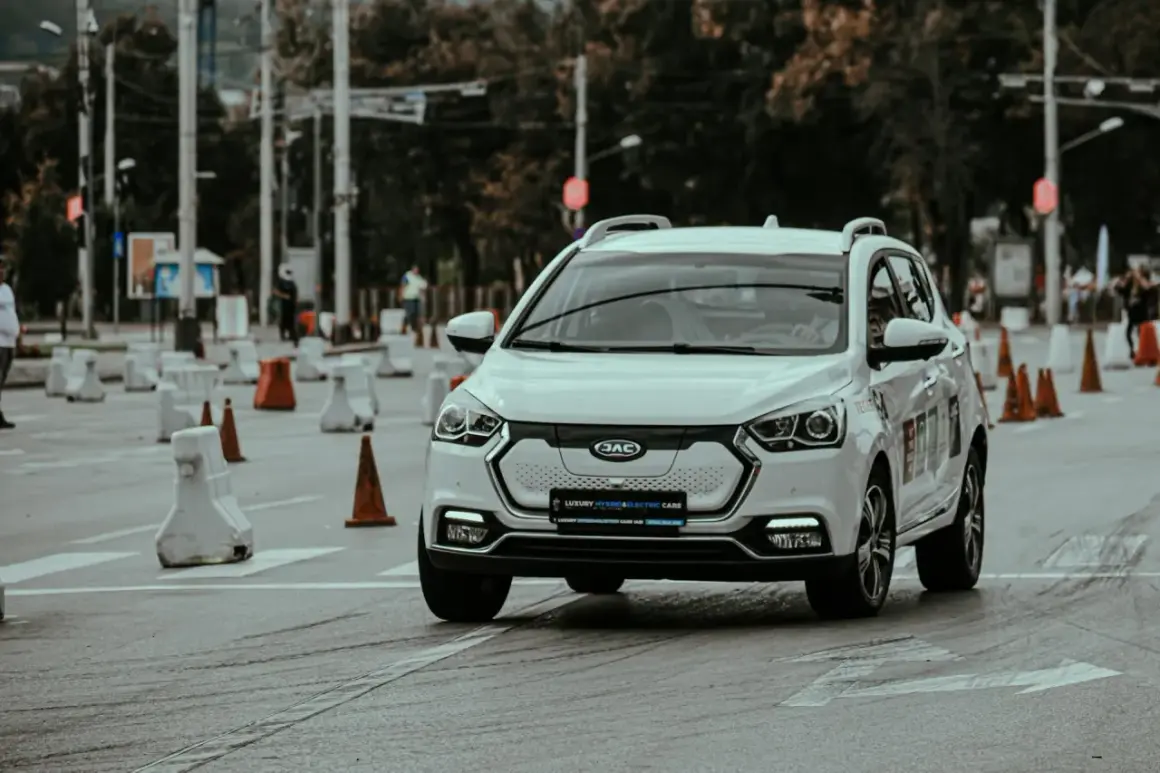 Voiture blanche lors d'un stage de sensibilisation à la sécurité routière, slalomant entre des cônes et des barrières.