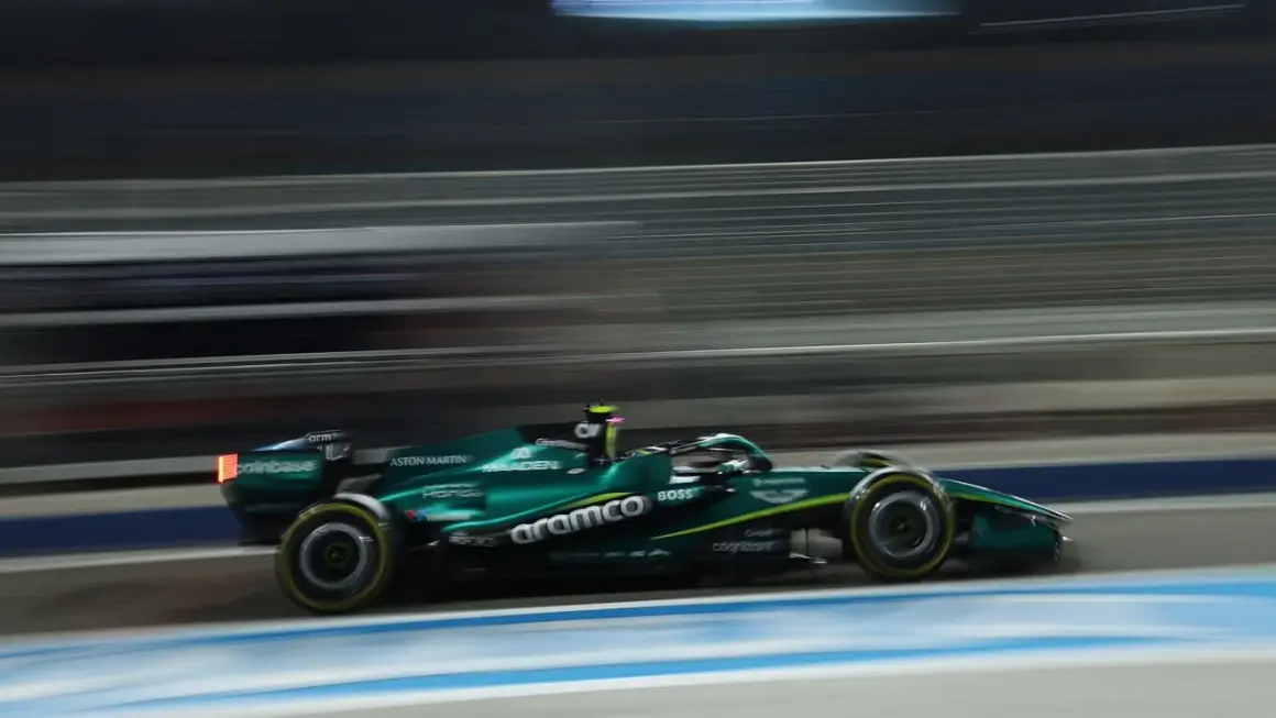 Un coche Aston Martin Honda verde compite a gran velocidad en una pista nocturna, con las luces y el fondo difuminados por el movimiento.