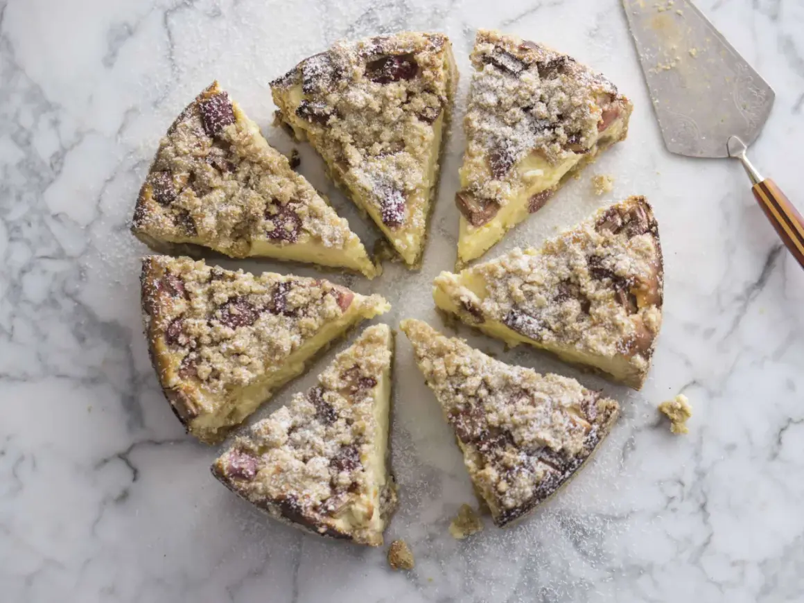Süßer Rhabarber Schmand Kuchen, in Stücke geschnitten, mit Puderzucker bestäubt, auf Marmorplatte.