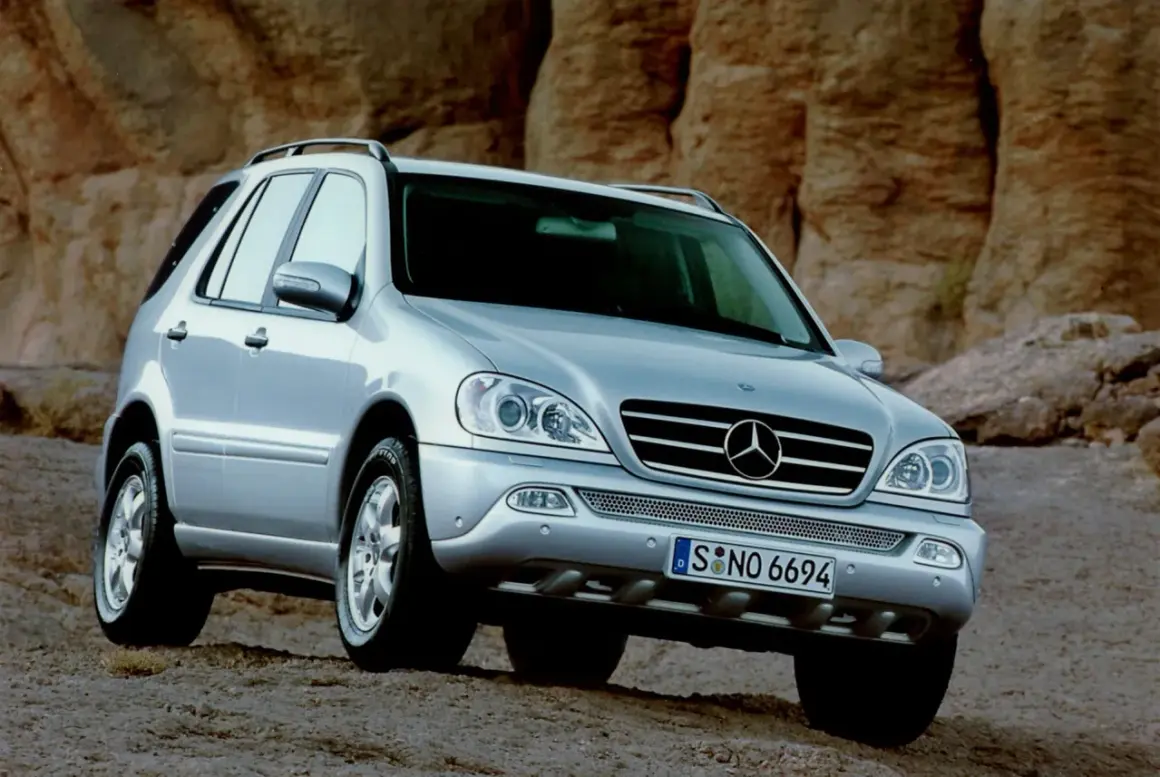 Srebrny Mercedes ML 320 na tle skalistego krajobrazu.