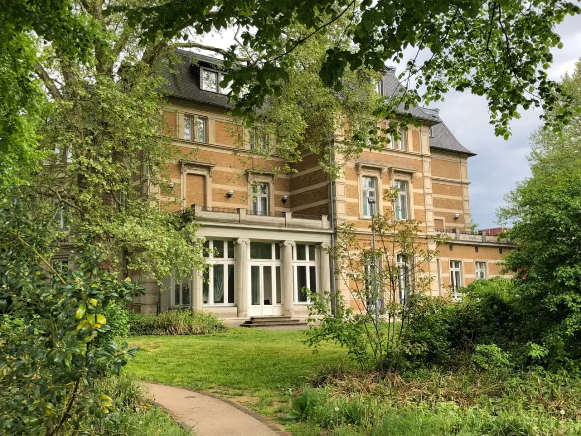 Prachtvolle Villa Zanders, umgeben von üppigem Grün, mit einem Weg, der sich durch den Garten schlängelt.