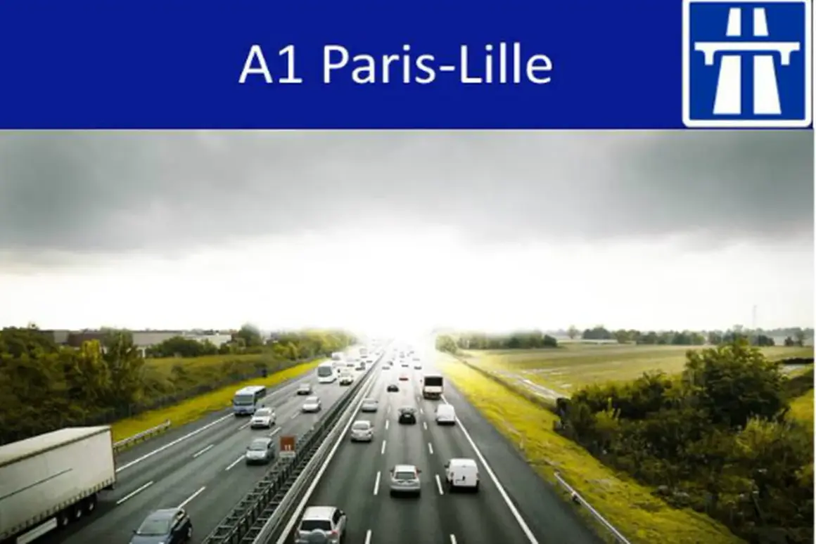 Trafic dense sur l'autoroute A1 Paris-Lille sous un ciel couvert. Des voitures et camions circulent sur plusieurs voies.