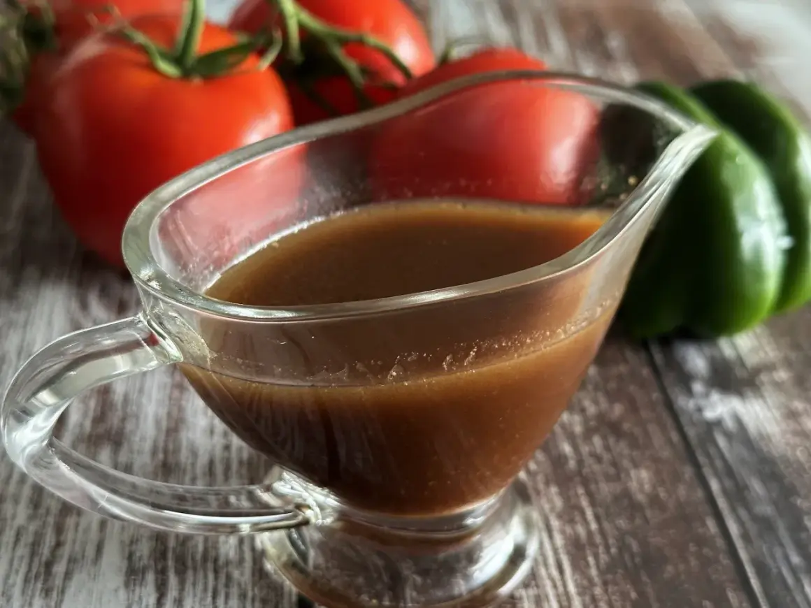 Sos balsamiczny w sosjerce, na tle pomidorów i zielonej papryki. Idealny do sałatek i mięs.