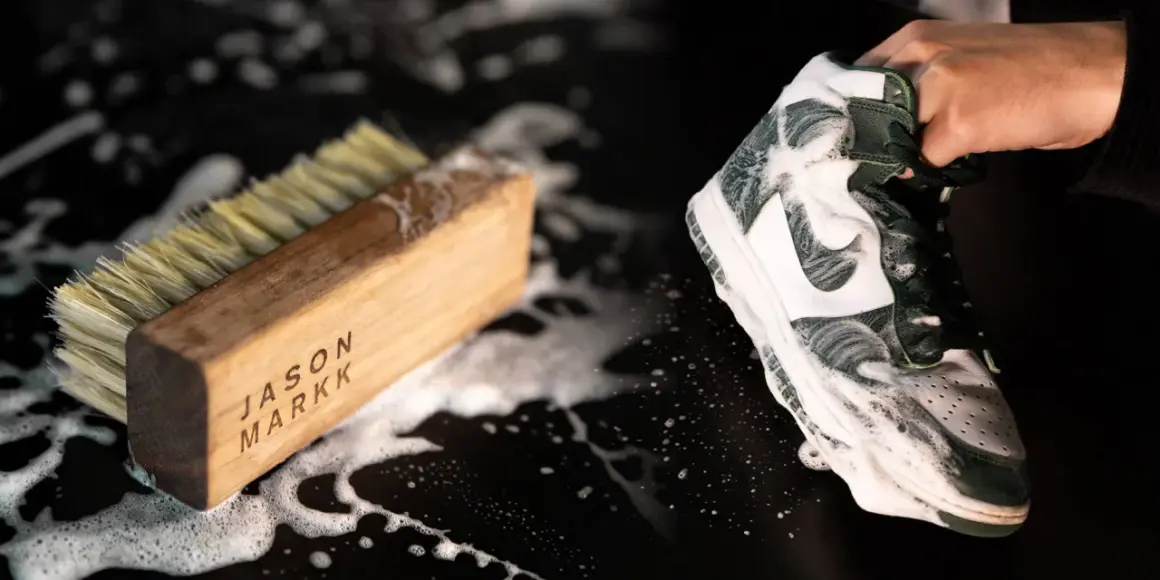 Une chaussure est savonneuse, prête à être nettoyée avec une brosse. Le processus pour **laver chaussures machine** est en cours.