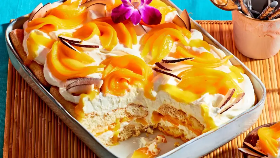 Ein cremiges Mango Tiramisu mit Kokosflocken und einer exotischen Orchidee verziert.