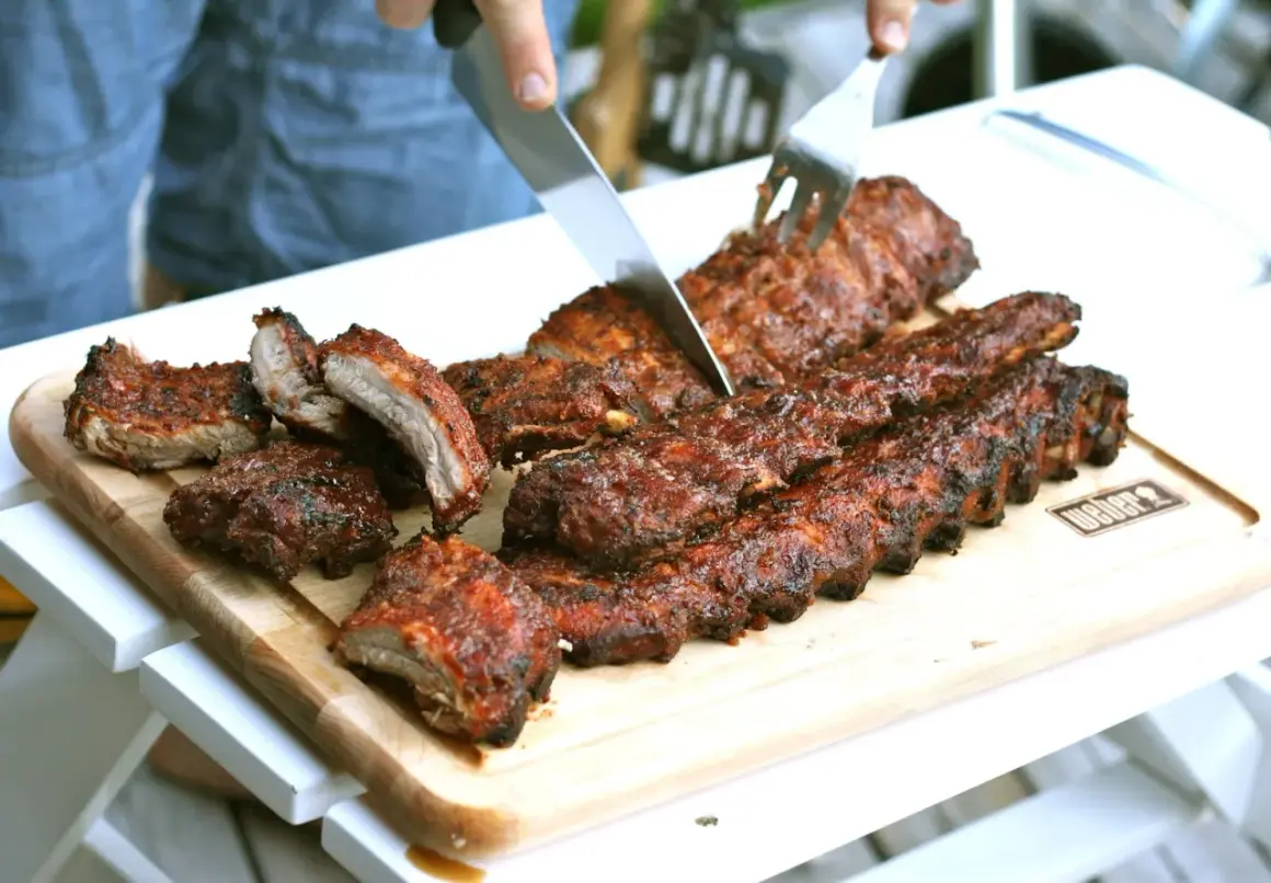 Grillade kamben skärs upp på en skärbräda. Saftiga och rökiga, redo att avnjutas.