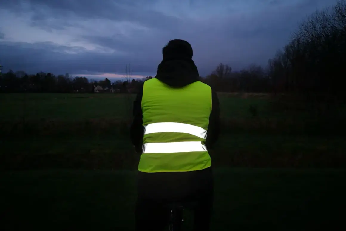 Person mit Warnweste Fahrrad im Dämmerlicht. Sichtbarkeit ist wichtig, auch wenn es nicht verboten ist.