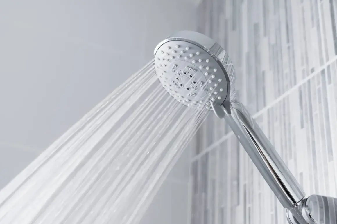 A chrome shower head sprays water, questioning if shower heads are universal.