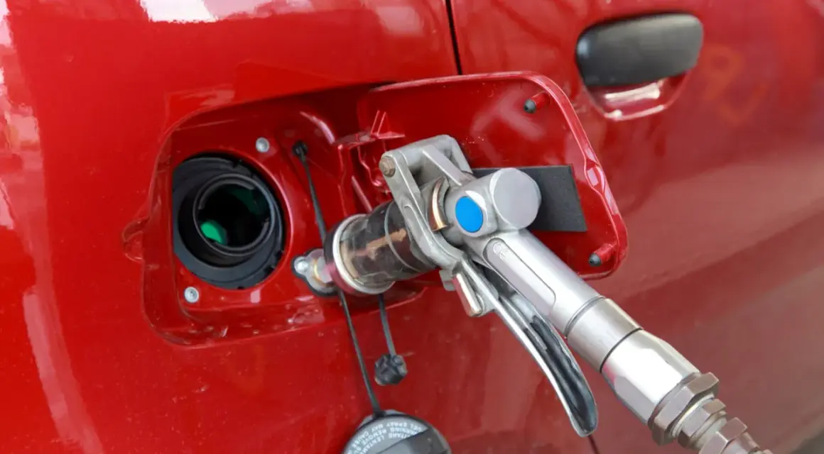 Remplissage d'une voiture rouge avec un pistolet GPL. Avis sur la bicarburation essence/GPL.