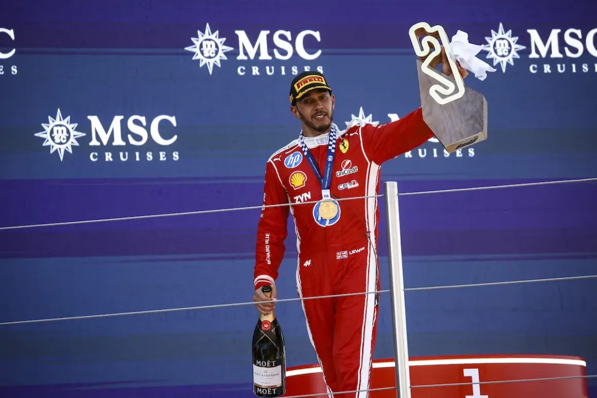 Lewis Hamilton celebra su victoria en el podio, con trofeo y champán. Su edad no se refleja en su energía.