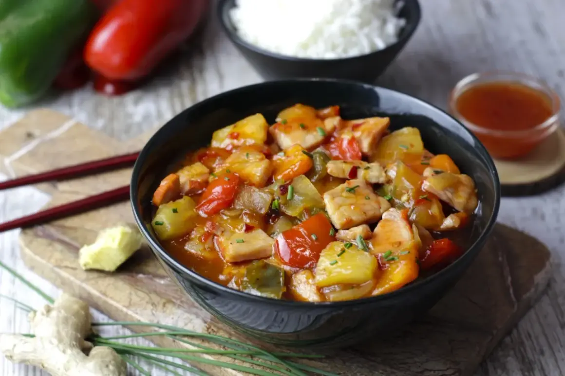 Sabroso wok de cerdo con trozos de piña, pimientos rojos y verdes, servido en un cuenco negro.