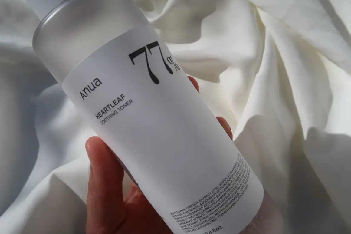 Anua Heartleaf Soothing Toner 77% w dłoni na tle białej tkaniny. Idealny do codziennej pielęgnacji.