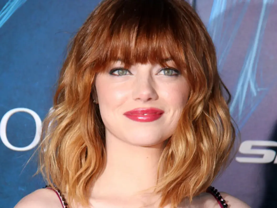 Emma Stone luce un vibrante pelo naranja en cascada, un estilo que realza su belleza natural.