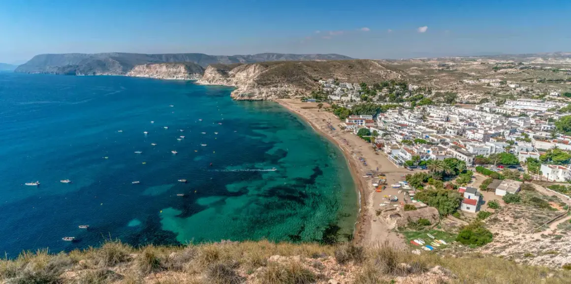 Vista aérea de la costa con aguas turquesas, barcos y el pueblo blanco de restaurante costamarga.