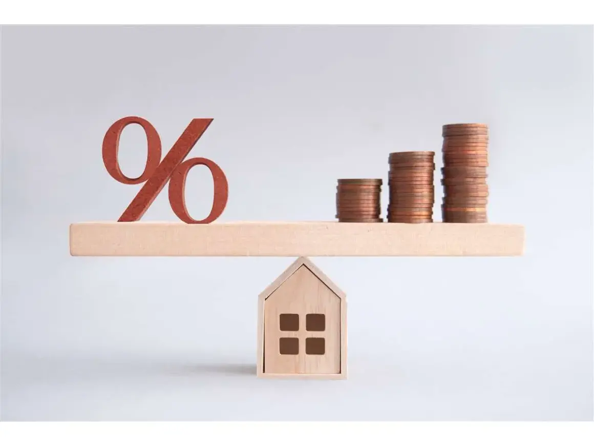Bilancia con simbolo percentuale e pile di monete su una casa. Un'illustrazione su come comprare una casa.